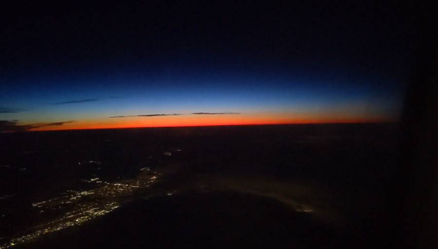 Photo of the horizon with a colorful sunset, taken from a plane window.