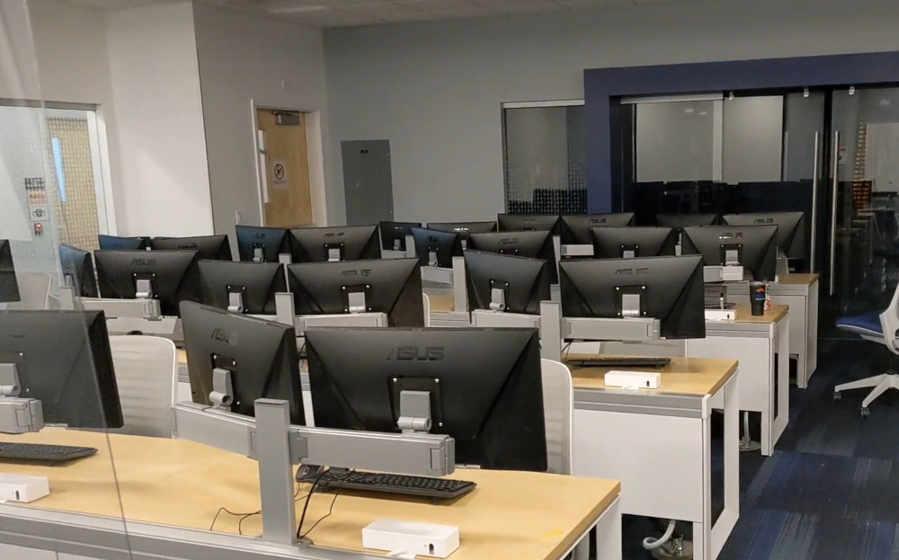 Computer room with many monitors and windows.